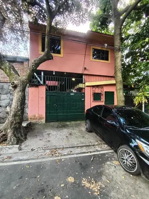 a black car parked in front of a pink house at Rooms libertad in San Salvador
