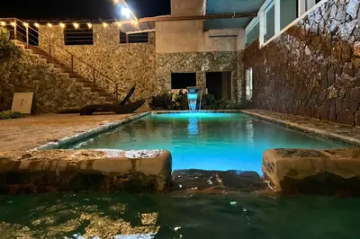 a swimming pool with blue water in a building at Hotel Termales La Montaña in Ahuachapán