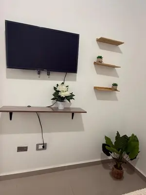 a flat screen tv on a wall with shelves at Descanso San Miguel in San Miguel