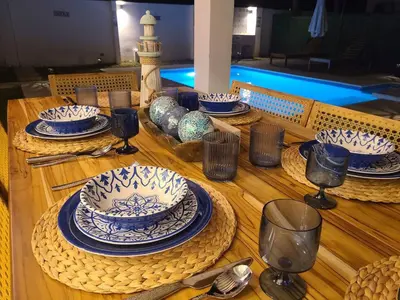 a wooden table with blue and white plates and wine glasses at Jasibe Oceanside in Amatecampo - Steps to beach - Flexible Checkout in El Porvenir