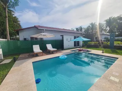 a swimming pool with two chairs and a house at Jasibe Oceanside in Amatecampo - Steps to beach - Flexible Checkout in El Porvenir