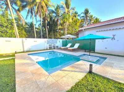 a swimming pool with a patio and an umbrella at Jasibe Oceanside in Amatecampo - Steps to beach - Flexible Checkout in El Porvenir