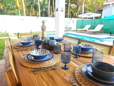 a wooden table with blue and white plates and wine glasses at Jasibe Oceanside in Amatecampo - Steps to beach - Flexible Checkout in El Porvenir