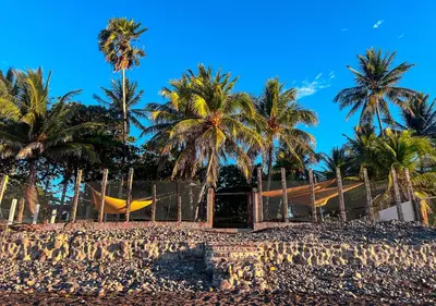 a hammock on a beach with palm trees at Quinta Brisas del Surf La Libertad in La Libertad