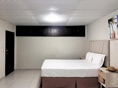 a bedroom with a large white bed with black cabinets at Quinta Brisas del Surf La Libertad in La Libertad