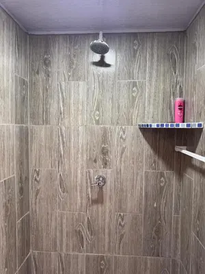 a bathroom with a wooden tile wall with a shower at Cocolandia Casa de campo cerca de Costa del sol en San Pedro Masahuat in San Pedro Masahuat