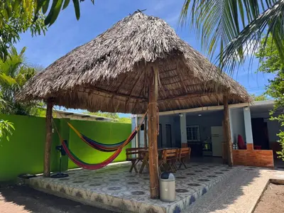 a hammock under a straw umbrella in front of a house at Cocolandia Casa de campo cerca de Costa del sol en San Pedro Masahuat in San Pedro Masahuat