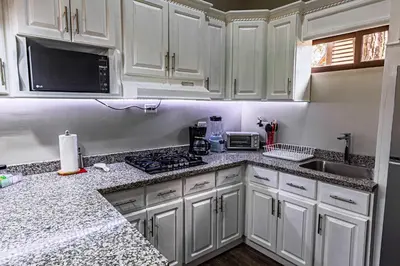 a kitchen with white cabinets and granite counter tops at Bungalos Vista a Cayaguanca in San Ignacio