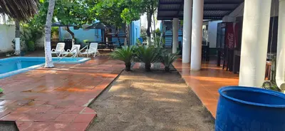 a patio next to a pool with chairs and trees at Hotel y Restaurante Los Cobanos Village Lodge in Los Cóbanos