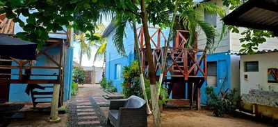 a blue building with a tree in front of it at Hotel y Restaurante Los Cobanos Village Lodge in Los Cóbanos