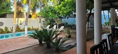 a resort with a pool and chairs and a palm tree at Hotel y Restaurante Los Cobanos Village Lodge in Los Cóbanos