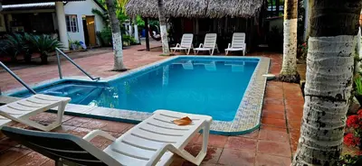 a swimming pool with lounge chairs and a table at Hotel y Restaurante Los Cobanos Village Lodge in Los Cóbanos