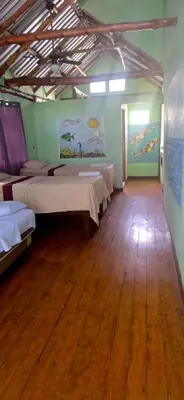 a room with three beds and a wooden floor at Hotel y Restaurante Los Cobanos Village Lodge in Los Cóbanos