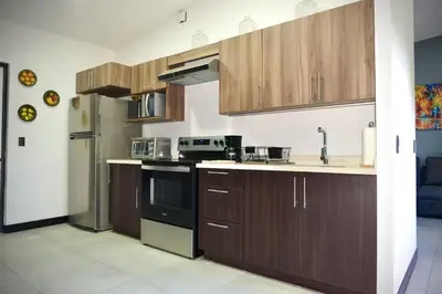 a kitchen with wooden cabinets and a stove top oven at Beautiful & Cozy Suite 3 min from Paseo Escalon in San Salvador