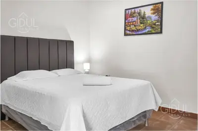 a bedroom with a bed with white sheets and a picture on the wall at Comfy Bedroom in a hostal at Coatepeque lake in El Congo