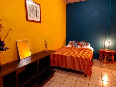 a bedroom with a bed and a desk with a mirror at Expresión cultural restaurante y alojamiento in Santa Ana