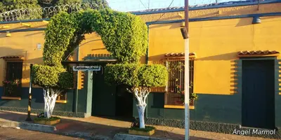 two trees in front of a yellow building at Expresión cultural restaurante y alojamiento in Santa Ana