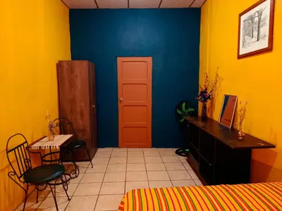 a bedroom with a blue and yellow wall and a table and chair at Expresión cultural restaurante y alojamiento in Santa Ana
