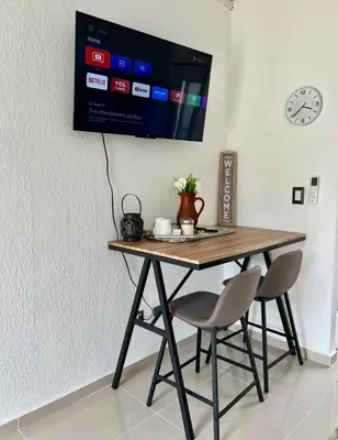 a table with two chairs and a tv on a wall at Ahuachapan Tiny Rental Homes in Ahuachapán
