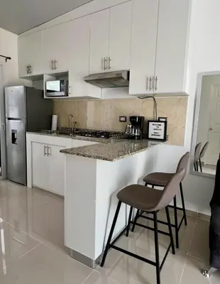 a kitchen with white cabinets and a counter and a stool at Ahuachapan Tiny Rental Homes in Ahuachapán