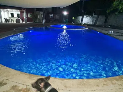 a large blue swimming pool at night at Rancho número 50 in La Libertad
