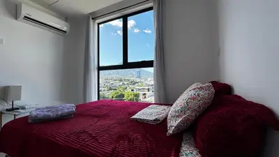 a bedroom with a red bed with a large window at Vista de la capital in San Salvador