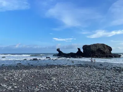 a rocky beach with a large rock in the ocean at Conchita House Playa El Tunco in Tamanique