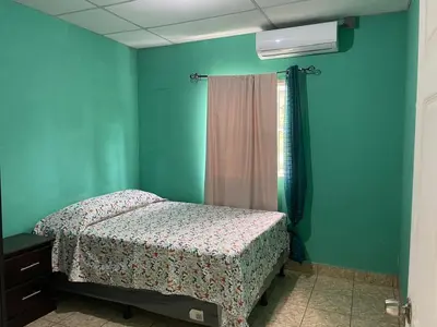 a bedroom with a bed and a green wall at Conchita House Playa El Tunco in Tamanique