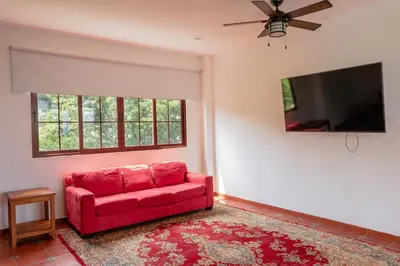 a living room with a red couch and a flat screen tv at Las Golondrinas El Zonte, El Salvador in El Zonte