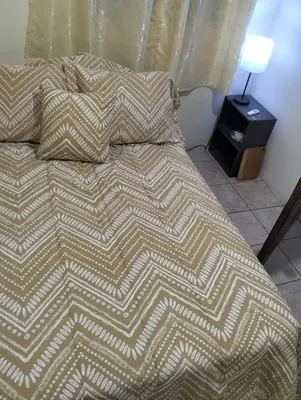 a bed with a blanket and pillows on it at Copinol 68 in San Salvador