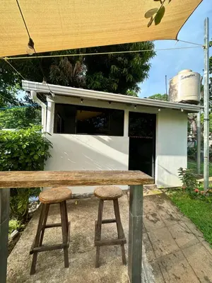 a wooden bench with two stools under an umbrella at Surfcity Townhouse in La Libertad