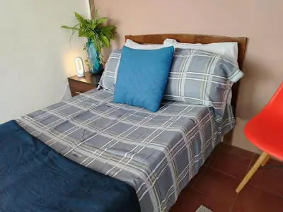 a bedroom with a bed with blue and gray pillows at Hostal Genoveva in San Salvador