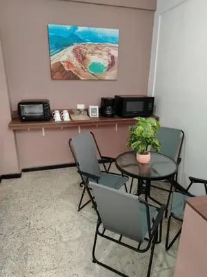 a table and chairs in a waiting room with a table and a plant at Hostal Genoveva in San Salvador