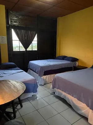 a room with three beds and a table and a window at El Balcón de Ataco in Concepción de Ataco