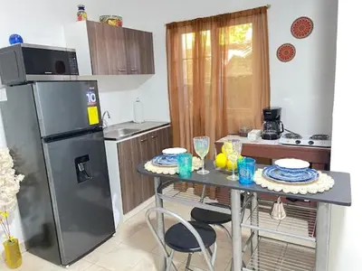 a kitchen with a table with chairs and a refrigerator at La ceiba surf in El Sunzal