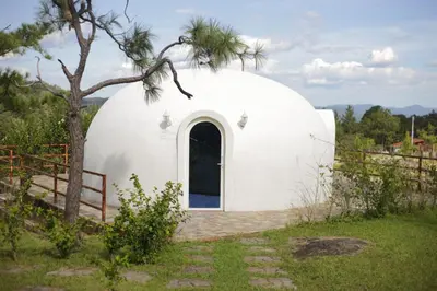 a round white dome house with a tree at Hotel y restaurante villa marquez in Perquín
