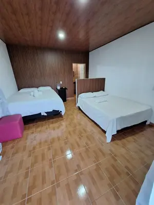 two beds in a room with wooden floors at Hotel y restaurante villa marquez in Perquín