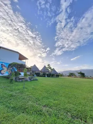 a grassy field with huts in the background at Hotel y restaurante villa marquez in Perquín