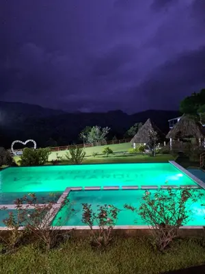 a swimming pool at night with a mountain in the background at Hotel y restaurante villa marquez in Perquín