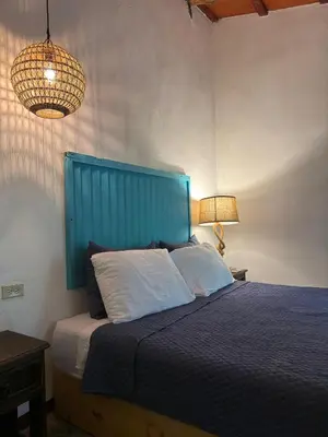 a bedroom with a bed with a blue headboard and two lamps at Casa FLamenco Suchitoto in Suchitoto