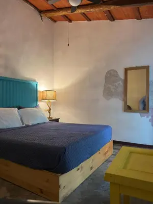 a bedroom with a bed and a table and a mirror at Casa FLamenco Suchitoto in Suchitoto