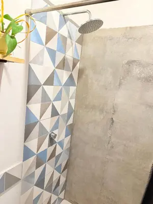 a shower in a bathroom with geometric tiles at Casa FLamenco Suchitoto in Suchitoto