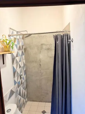 a shower with a blue shower curtain in a bathroom at Casa FLamenco Suchitoto in Suchitoto