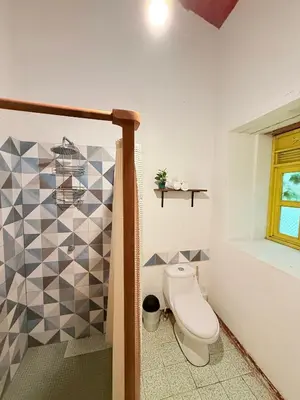 a bathroom with a toilet and a tile wall at Casa FLamenco Suchitoto in Suchitoto