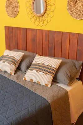 a bed with two pillows and a yellow wall at Cadejo Brewing Company El Sunzal in Tamanique