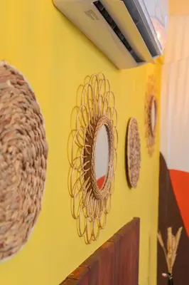 a yellow wall with three wicker mirrors on it at Cadejo Brewing Company El Sunzal in Tamanique