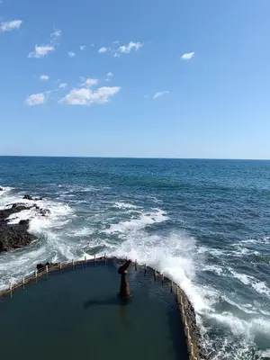 a person standing on a pier in the ocean at Cadejo Brewing Company El Sunzal in Tamanique