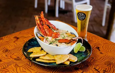 a bowl of shrimp and chips and a glass of beer at Cadejo Brewing Company El Sunzal in Tamanique