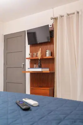 a room with a bed and a television and a door at Cadejo Brewing Company El Sunzal in Tamanique