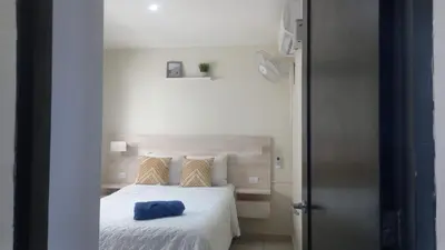 a bedroom with a white bed with a blue pillow on it at Great San Salvador views at Los Planes wifi and Ac in San Salvador